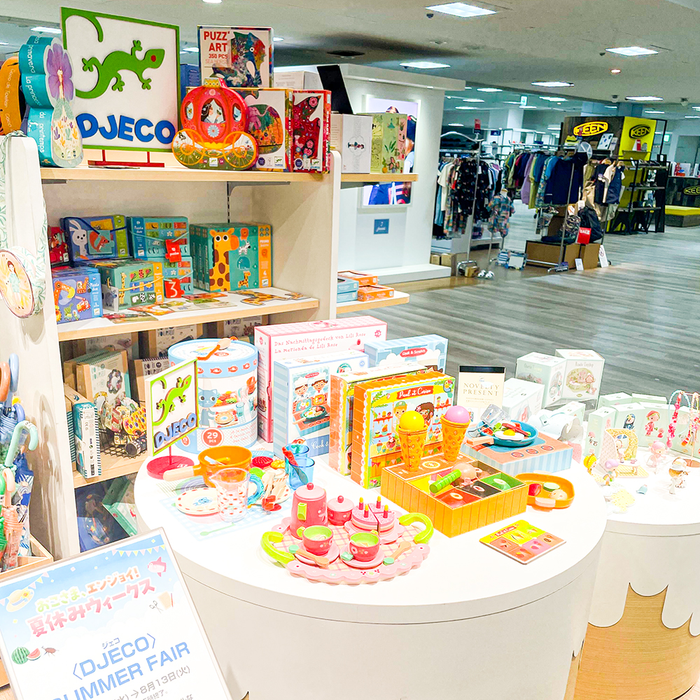 京都髙島屋のフェアの様子です。ケーキを模したディスプレイ台の上に、アクセサリーキットやティーニーのお人形が並んでいます。奥の棚には、おままごとのおもちゃやジグソーパズルが並んでいます。