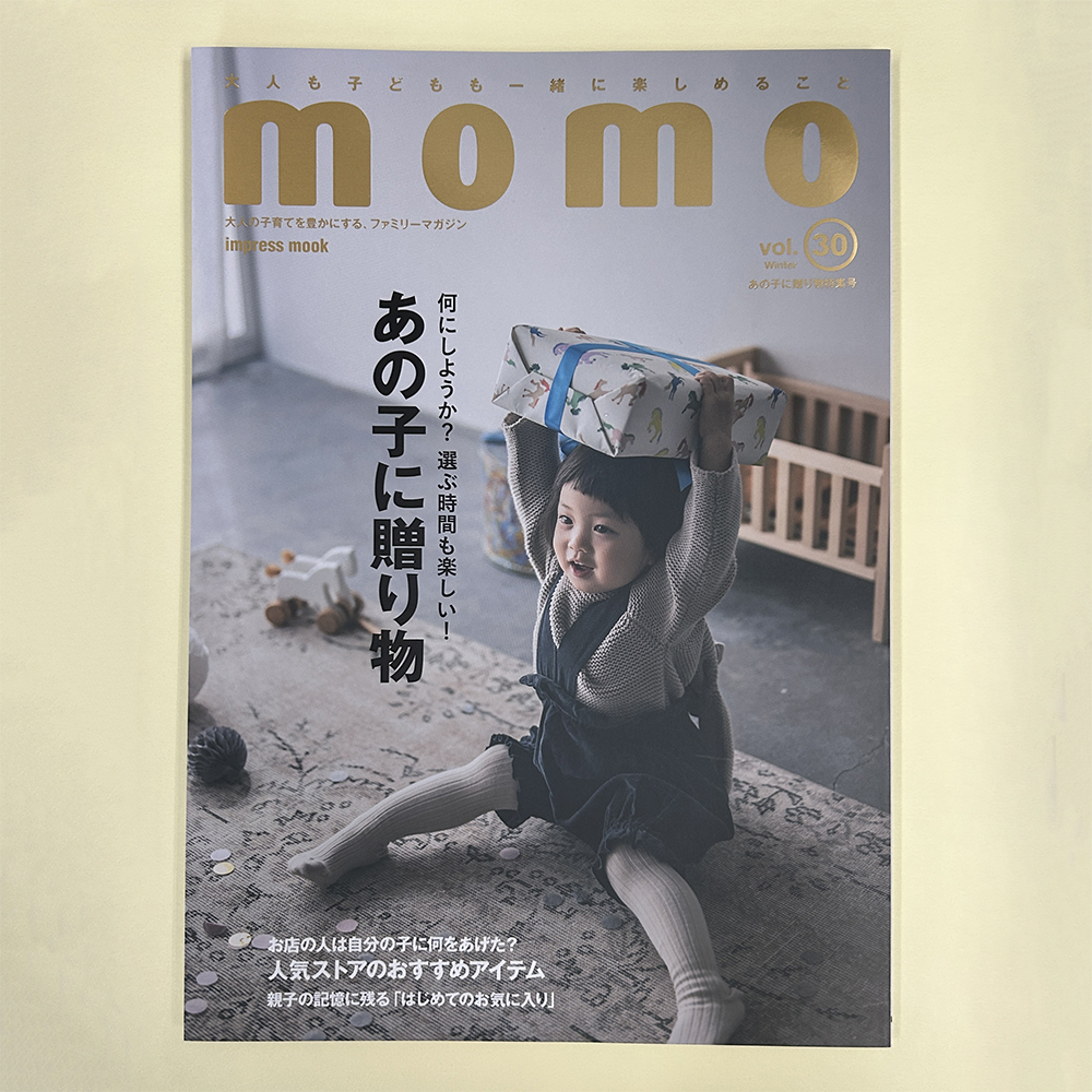momo vo;.30の表紙です。子どもが嬉しそうな顔でプレゼントを持ち上げています。